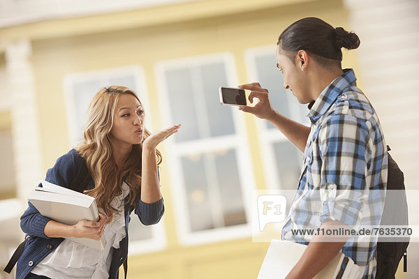 Man taking picture of girlfriend blowing kiss