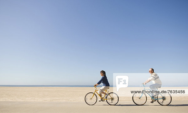 Paar fährt Fahrrad am Strand
