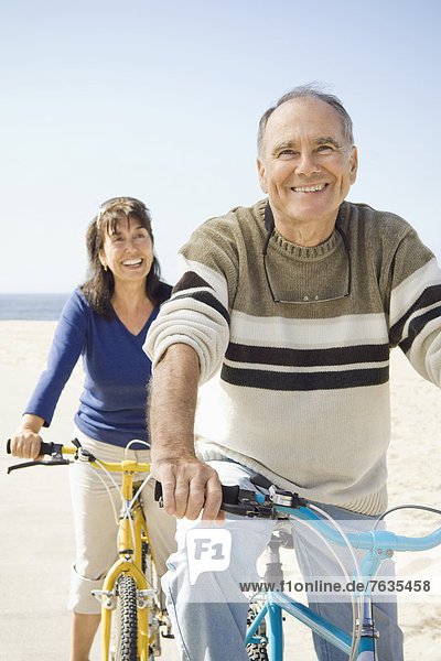 Couple sitting on bicycles on beach