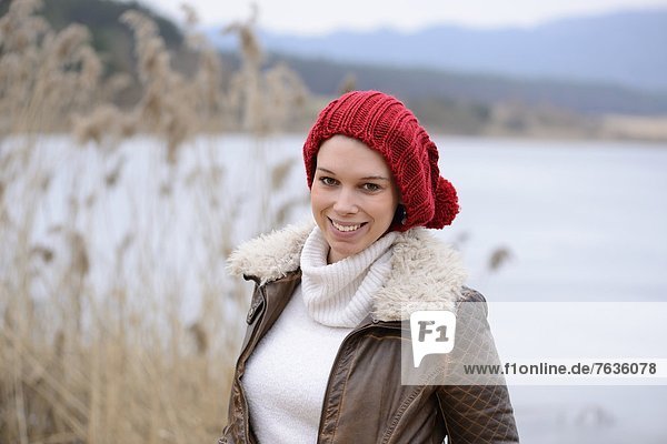 Lächelnde junge Frau an einem See  Porträt