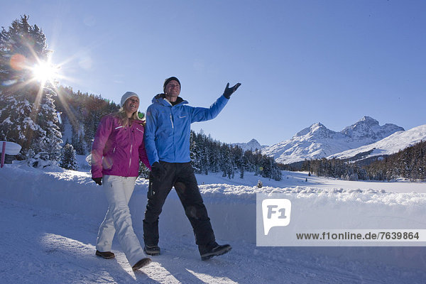Frau Winter Mann gehen Weg wandern Kanton Graubünden Wanderweg Sonne trekking Wintersport