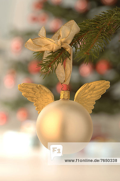 Silberne Christbaumkugel mit goldenen Engelsflügeln an Weihnachtsbaum