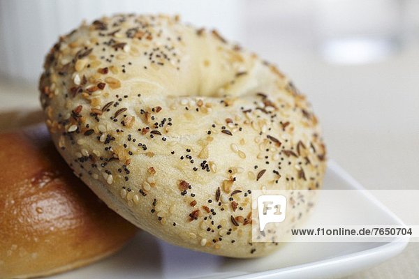 An Everything Bagel Leaning on a Plain Bagel