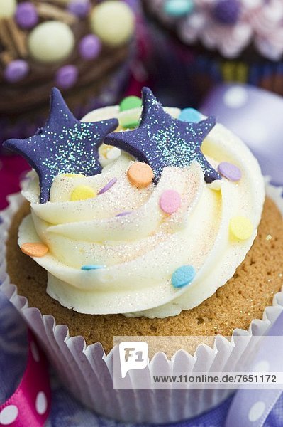 Vanille-Cupcake mit blauen Sternen  Glitter und Zuckerkonfetti
