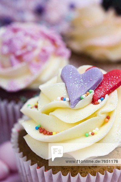 Vanille-Cupcake mit Herzen und bunten Zuckerperlen