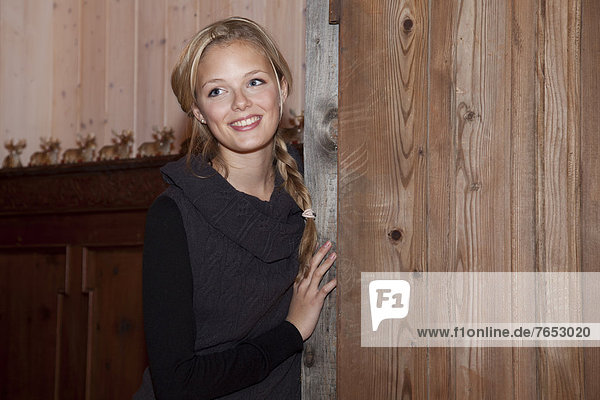 Smiling young woman leaning against a old door