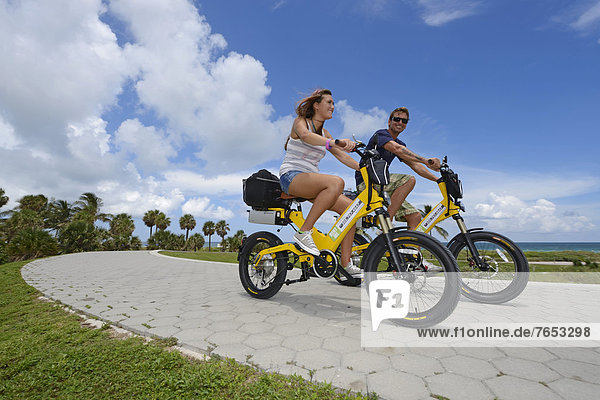 Couple riding electric bicycles  South Pointe Park  South Beach  Miami  Florida  USA