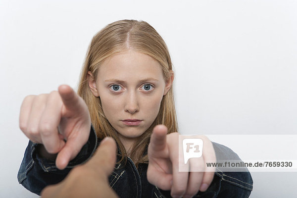 Young woman pointing fingers accusingly at person in foreground