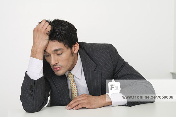 Mid-adult businessman holding head with eyes closed