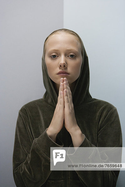 Junge Frau mit im Gebet umklammerten Händen  Porträt