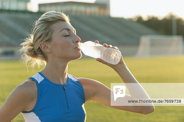 Sportlerin beim Trinken von Wasser in Flaschen