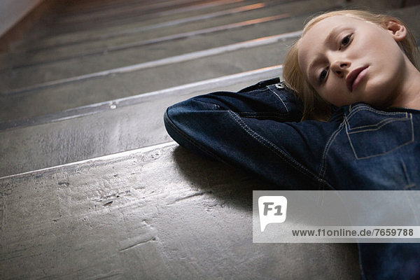 Young woman lying on stairs with hands behind head  portrait