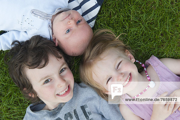 Young siblings lying on grass  portrait