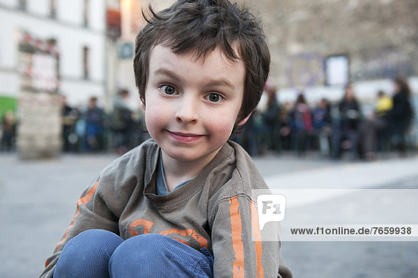 Boy sitting outdoors in urban setting  portrait