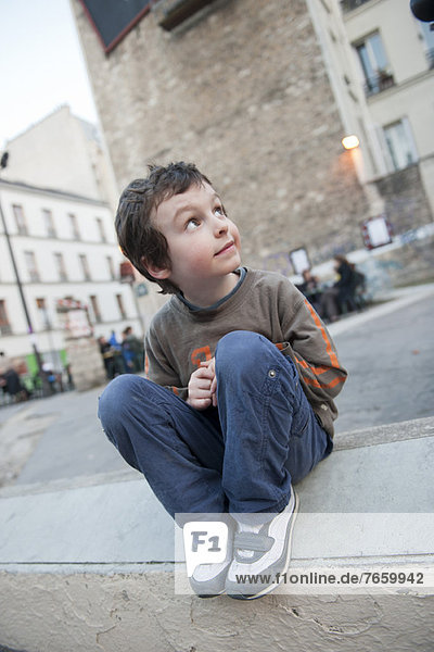 Boy sitting on curb  looking up
