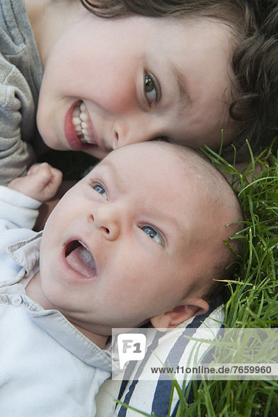 Boy lying on grass with baby brother  portrait