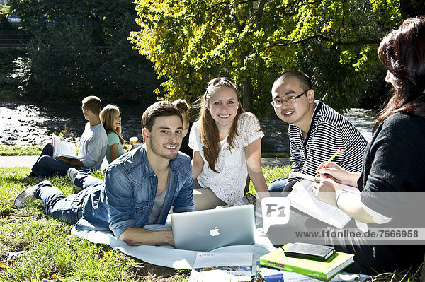 Students with a laptop and books on a meadow  Freiburg im Breisgau  Baden-Wuerttemberg  Germany  Europe
