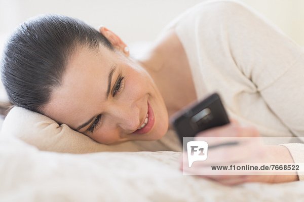 Woman lying on bed and using phone