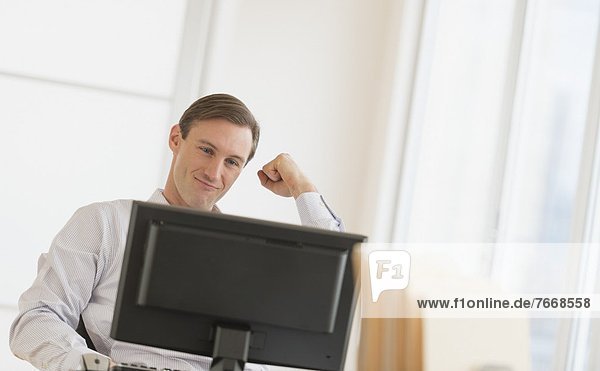 Office worker cheering in front of computer