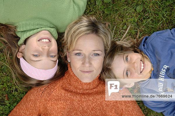 Mutter und Töchter liegt Kopf an Kopf im Gras