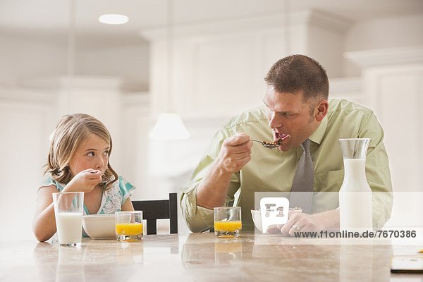 Father and daughter (6-7) eating breakfast