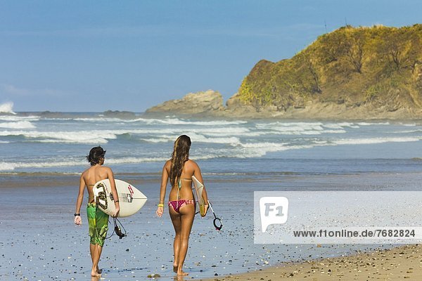 Boy and girl with surfboards at Playa Guiones beach  Nosara  Nicoya Peninsula  Guanacaste Province  Costa Rica  Central America