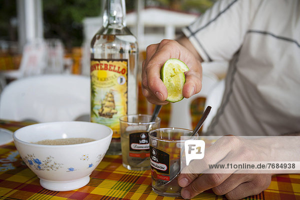 Ti-Punch  Zubereitung des Nationalgetränks mit Limone  Rohrzucker und Rum  Guadeloupe  Karibik  Kleine Antillen