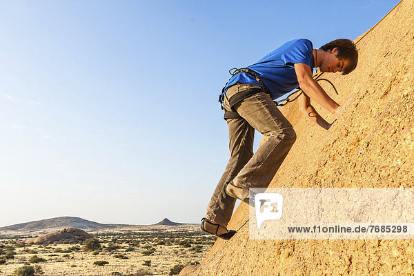 Young man climbing at Bogenfels  Spitzkoppe area  Damaraland  Namibia  Africa