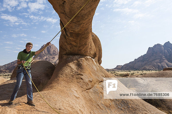 Young man hanging from a climbing rope  Bogenfels  Spitzkoppe area  Namibia  Africa