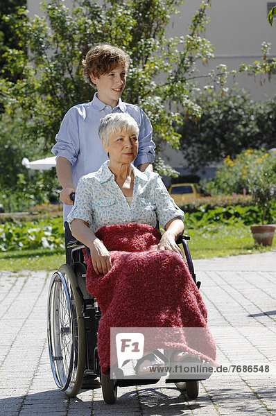 Enkel fährt Oma im Rollstuhl spazieren
