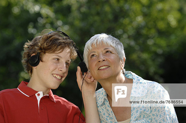 Oma und Enkel hören zusammen an einem Kopfhörer Musik