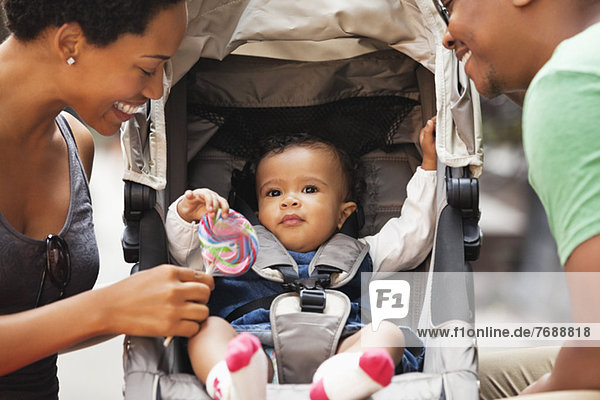 Eltern im Gespräch mit dem Baby im Kinderwagen auf der City Street