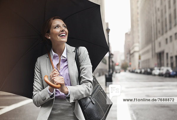 Geschäftsfrau mit Regenschirm auf der Stadtstraße