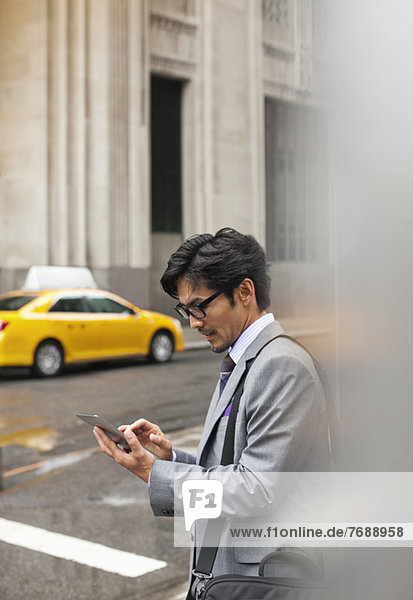 Businessman using tablet computer on city street
