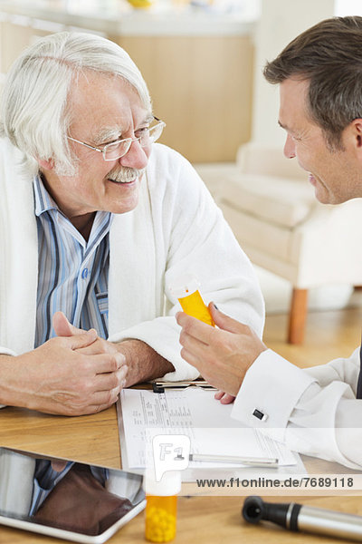 Arzt,  der älteren Patienten beim Hausbesuch Medikamente verabreicht.