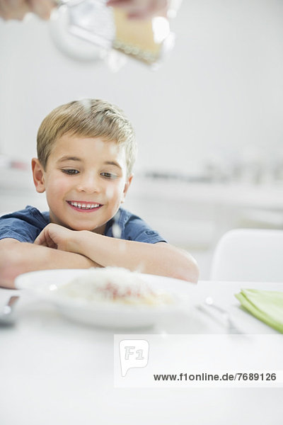 Smiling boy having spaghetti at table