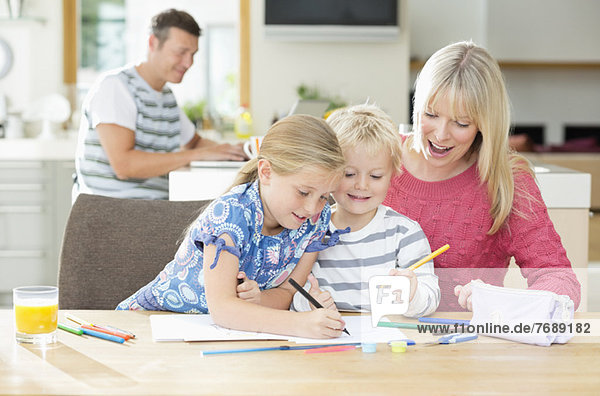 Mutter und Kinder beim Malen am Tisch