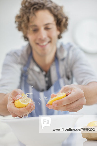 Man squeezing lemons in kitchen