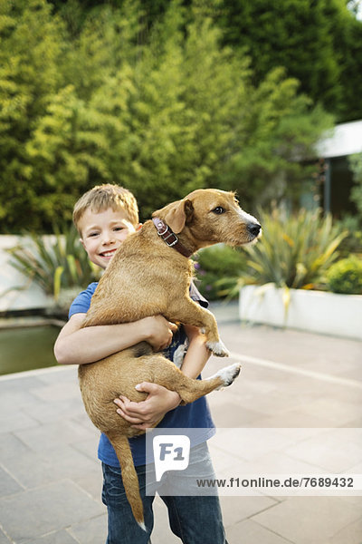 Smiling boy holding dog outdoors