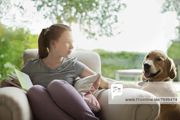 Mädchen entspannt mit Hund im Sessel