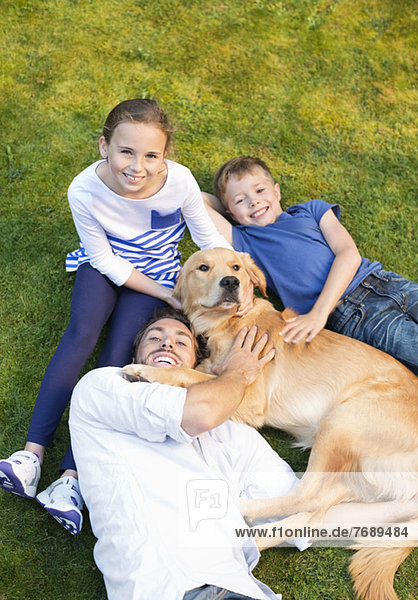 Family relaxing with dog on lawn