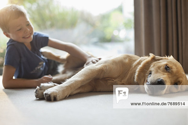 Smiling boy petting dog in living room