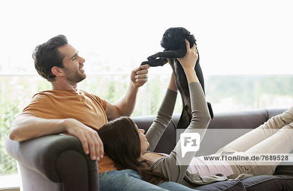 Couple relaxing with dog on sofa