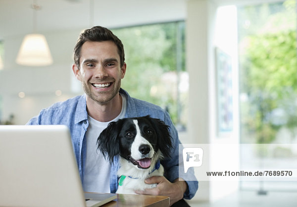 Man with dog using laptop in kitchen