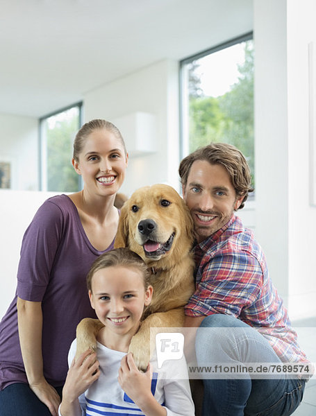 Familie lächelt mit Hund im Haus