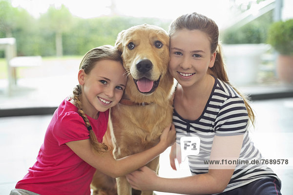 Lächelnde Mädchen umarmen Hund im Haus