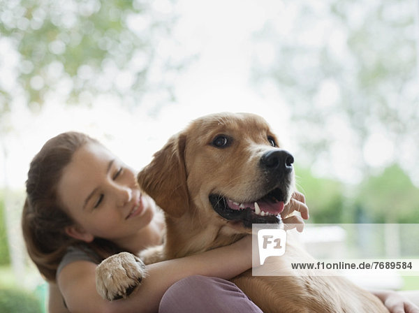 Lächelndes Mädchen umarmt Hund im Freien
