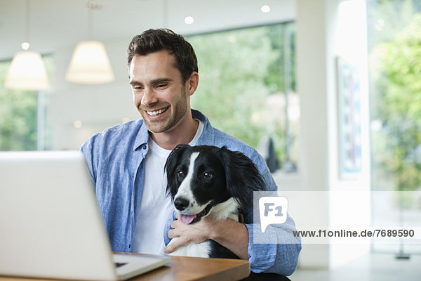 Man with dog on lap using laptop