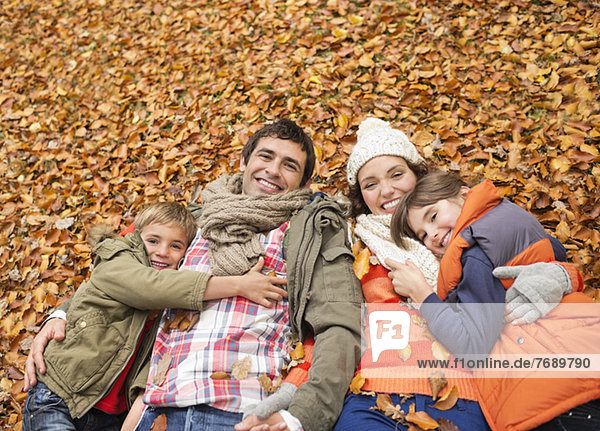 Smiling family laying in autumn leaves