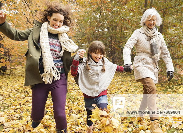 Drei Generationen von Frauen spielen im Herbstlaub